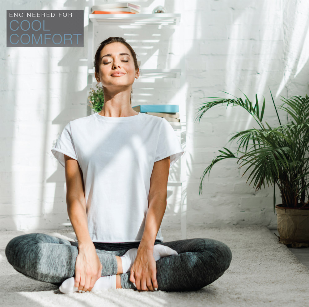 ENGINEERED FOR COOL COMFORT. Woman doing Yoga enjoying comfort of Rheem RA16AY Endeavor™ Line Classic Plus Series Air Conditioners
