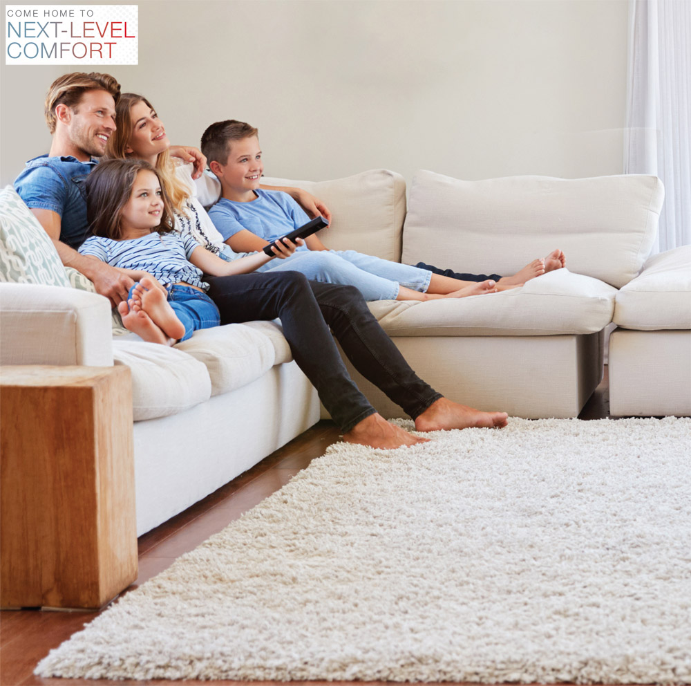 COME HOME TO NEXT-LEVEL COMFORT. Happy family on couch enjoying comfort of Rheem RP14AY Endeavor™ Line Classic Series Heat Pump